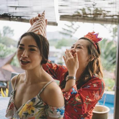 een openhartig moment waarop een Aziatische Chinese vrouw haar zus helpt de feestmuts vast te binden en zich klaarmaakt voor het verjaardagsfeestje