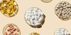 verschillende pillen en capsules, vitamines en voedingssupplementen in petrischalen op een beige achtergrond